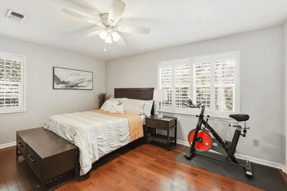 Modern bedroom with white bedding and bike.