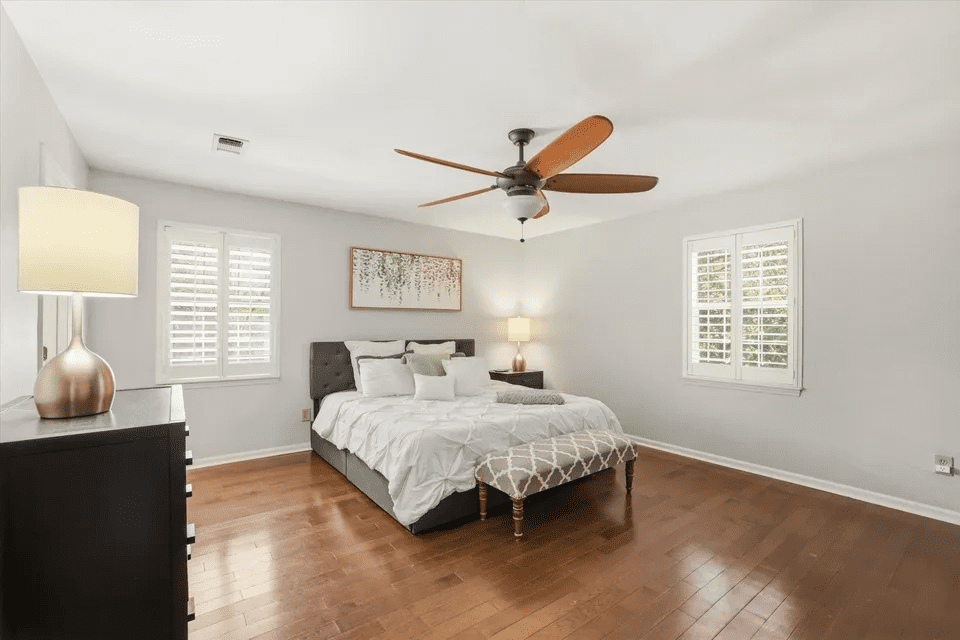 Modern bedroom with ceiling fan and artwork.