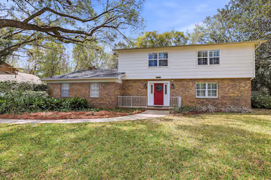 Two-story suburban house with a red front door and brick exterior.