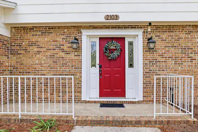 A red front door with a wreath on a brick house.