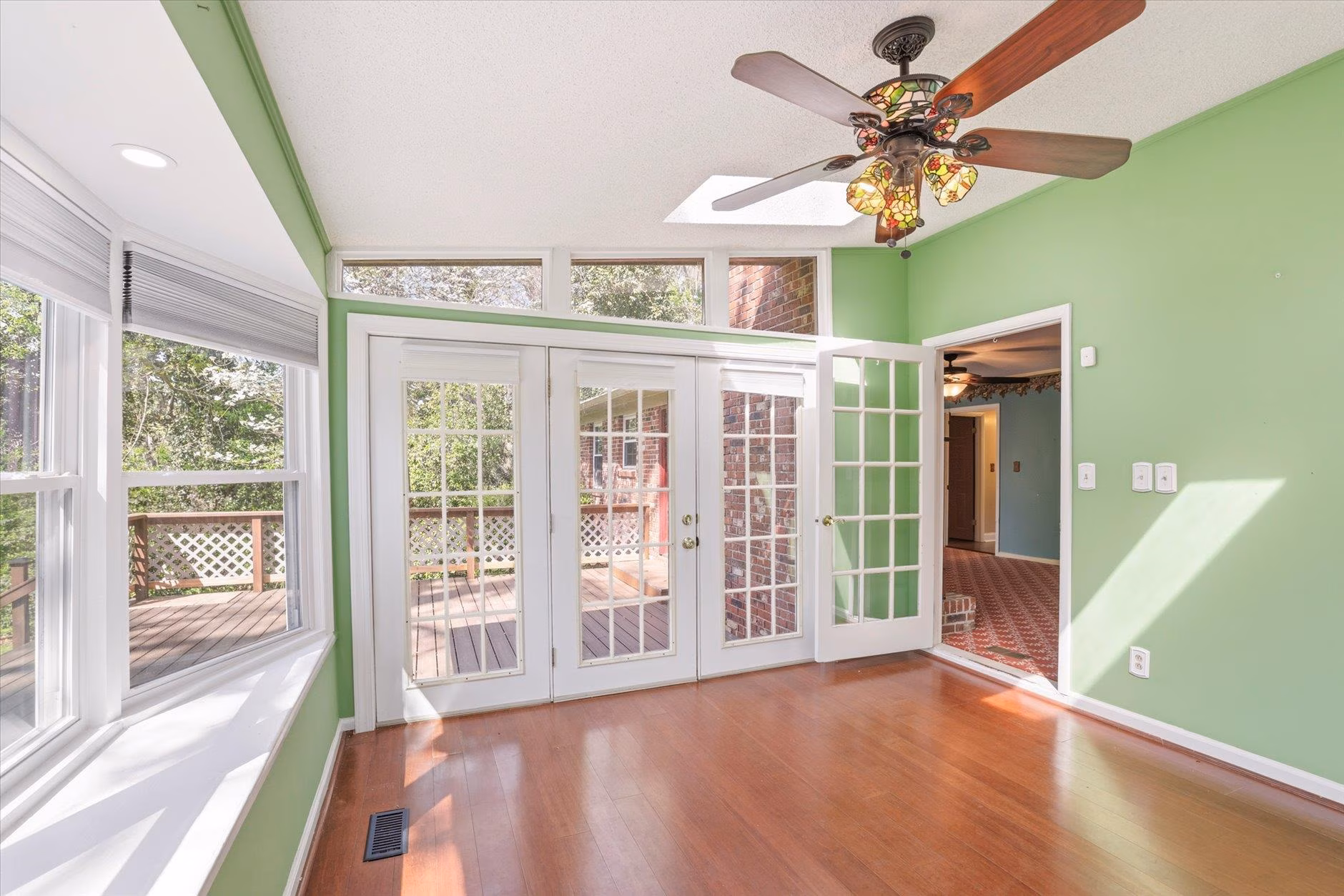 Bright sunroom with green walls and wooden floor.