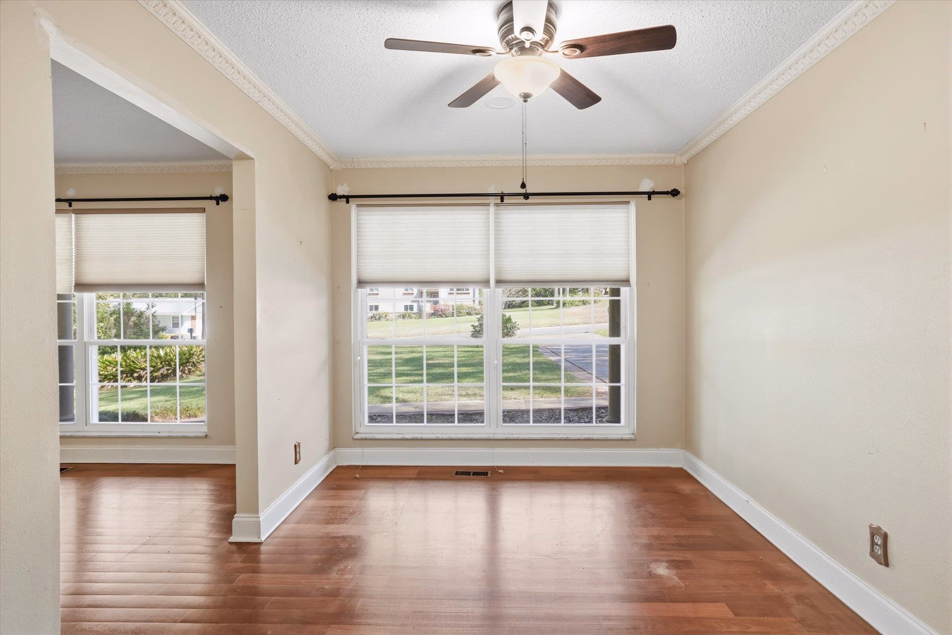 Bright empty room with wooden floors and large window.