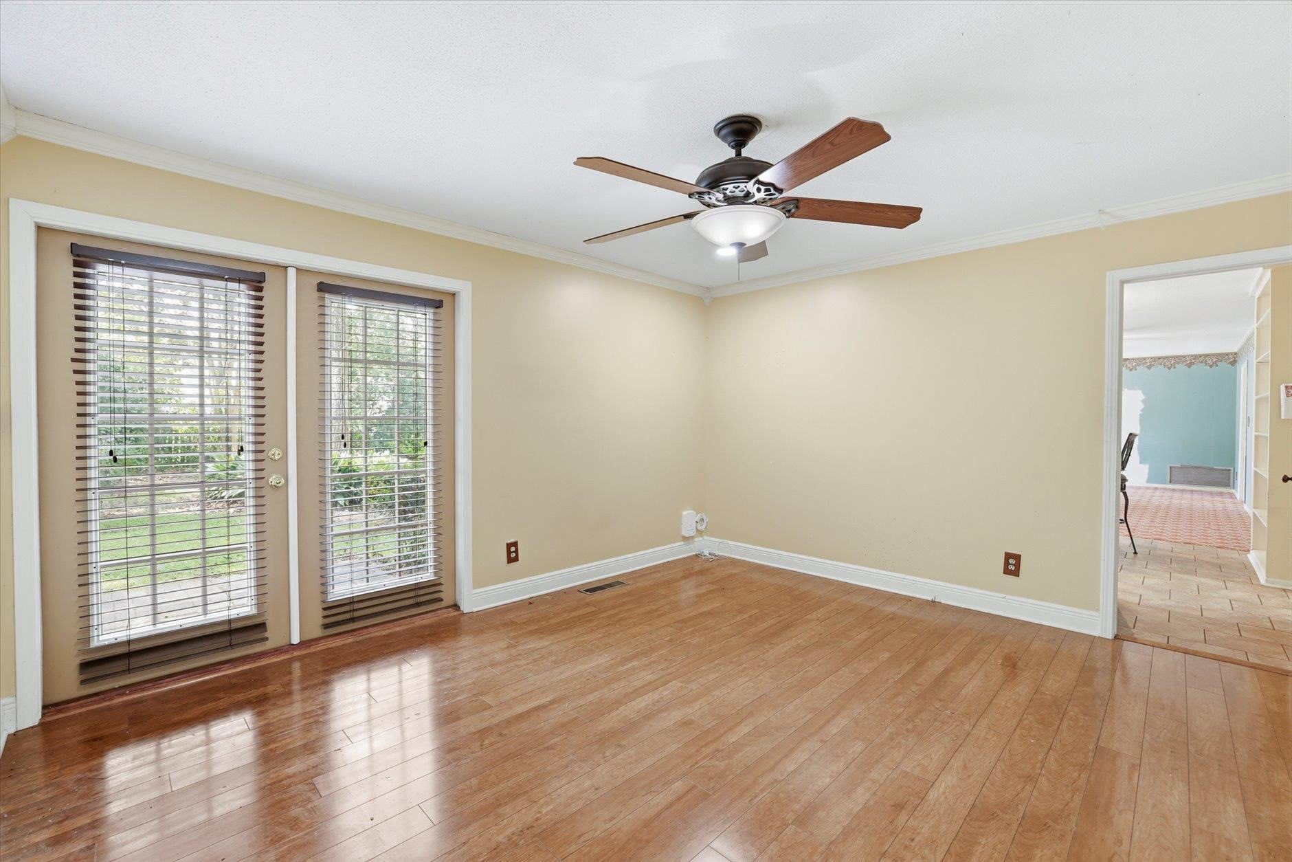 Empty room with hardwood floors and ceiling fan.