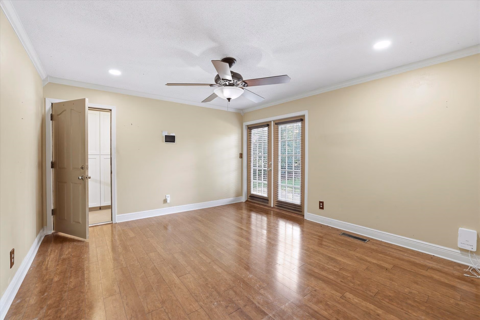 Empty room with hardwood floors and ceiling fan.