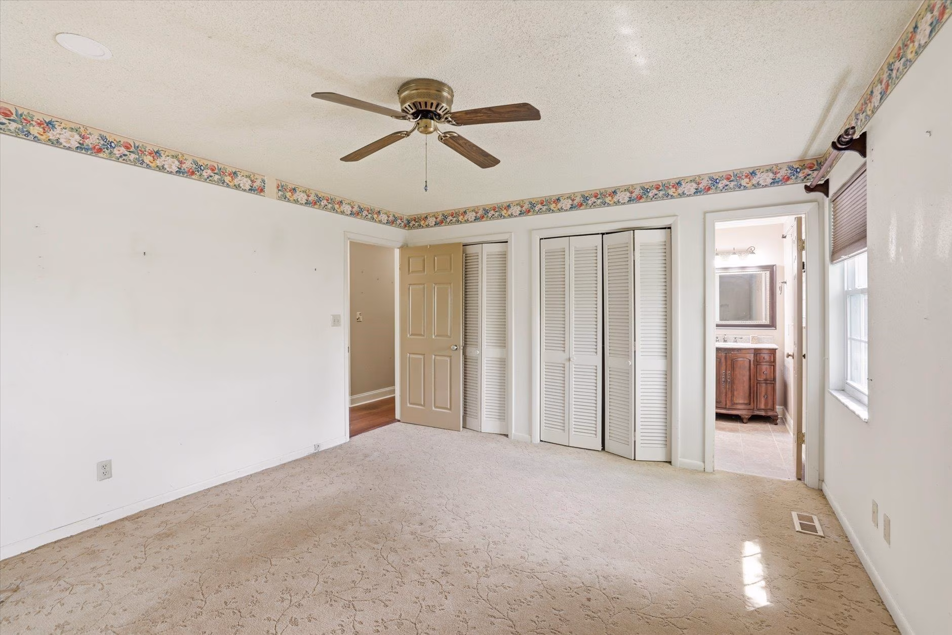 Empty room with ceiling fan and carpeted floor.