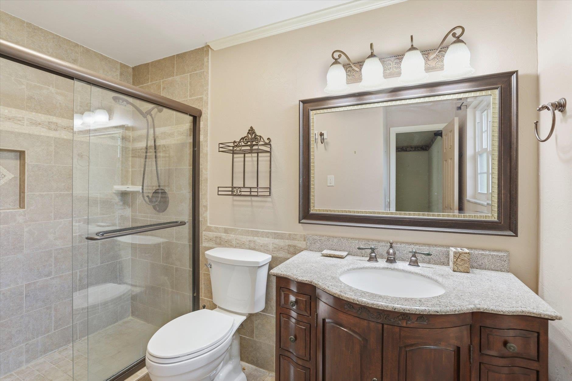 Elegant bathroom with wooden vanity and glass shower enclosure.