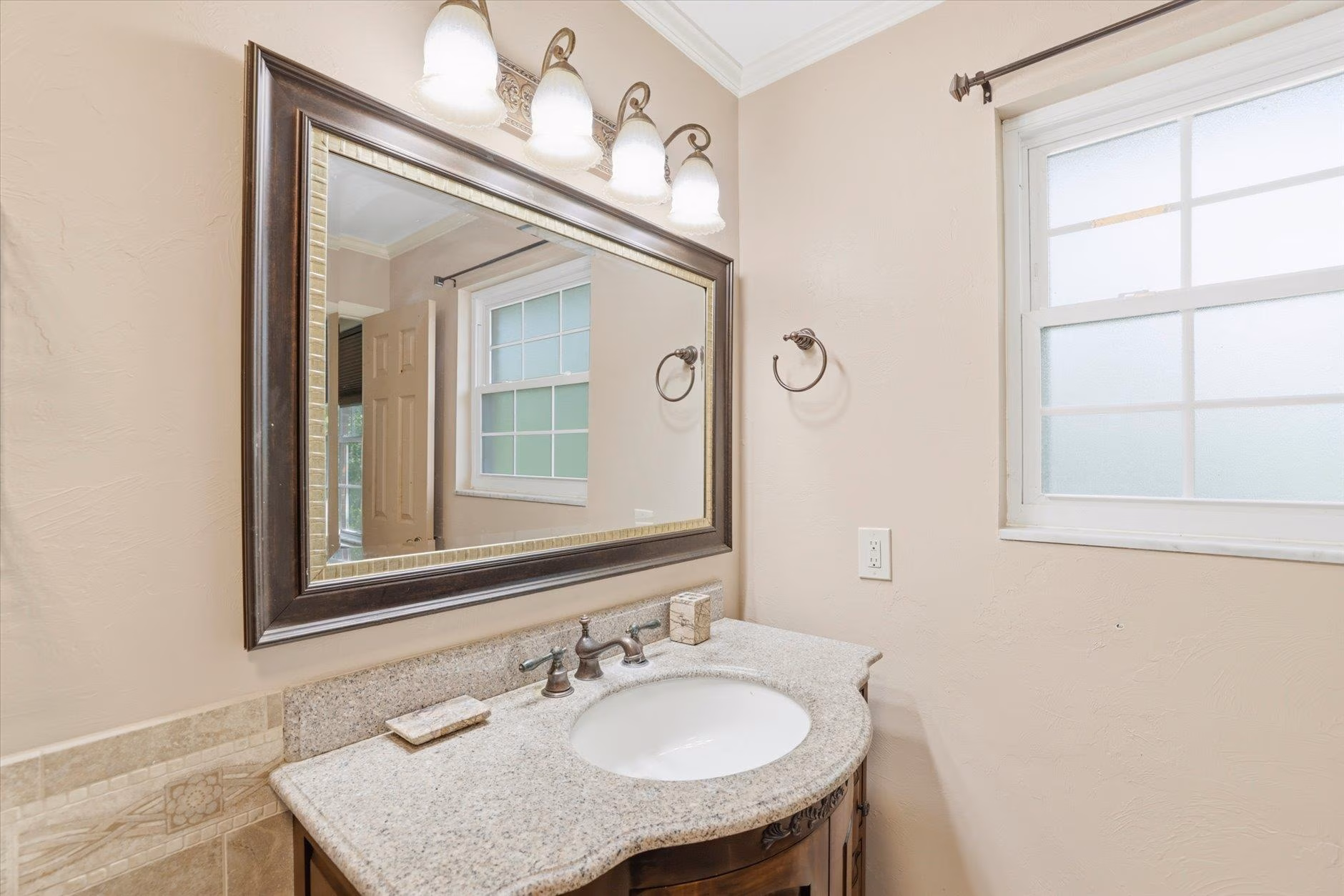 Elegant bathroom sink with granite countertop and large framed mirror.