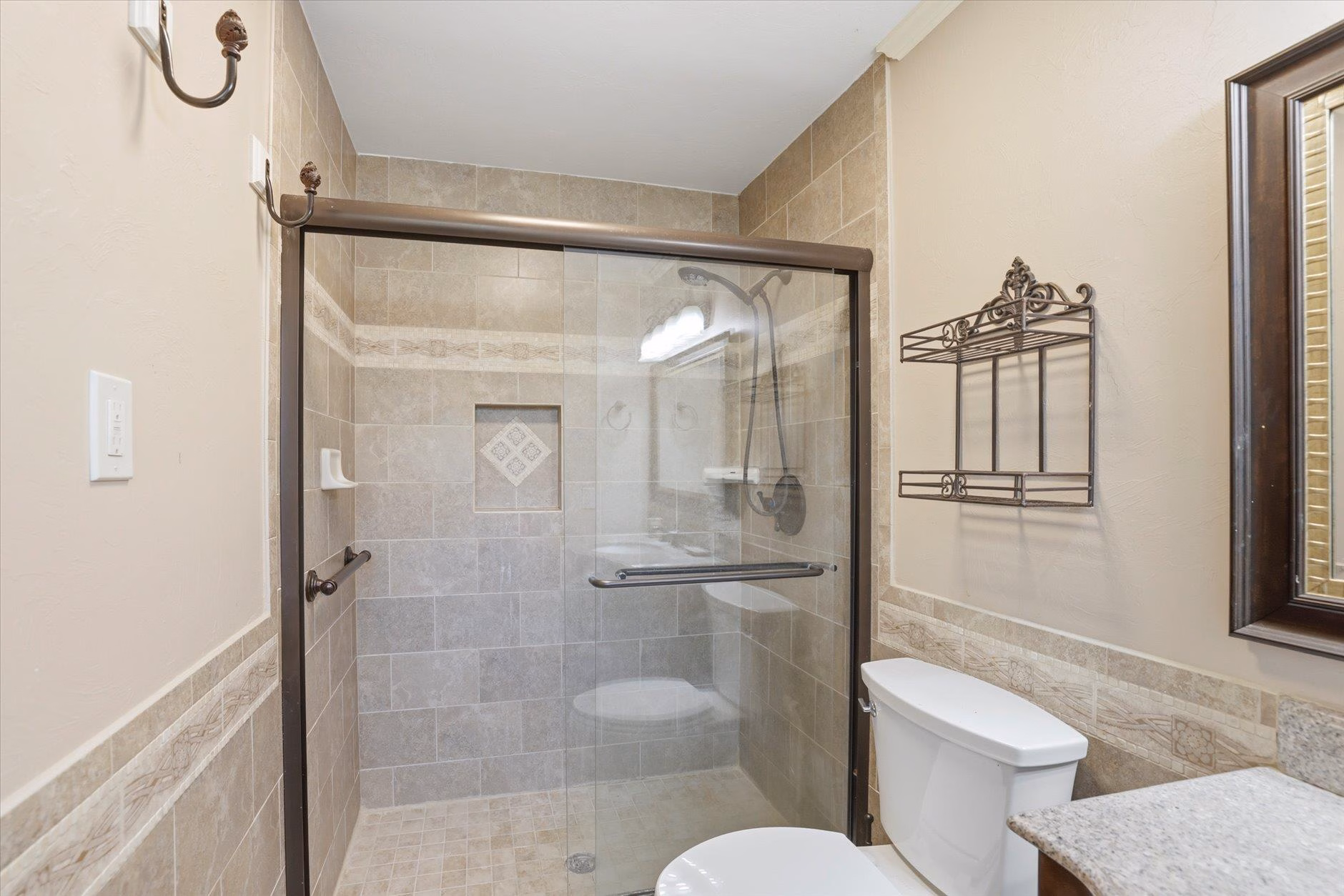 Modern bathroom with glass shower enclosure and neutral tones.