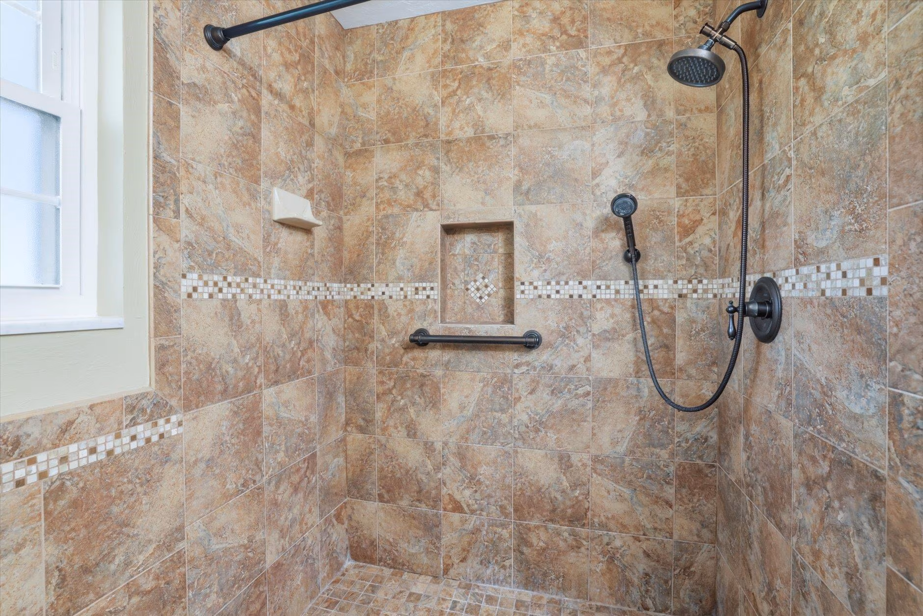 Modern shower with beige stone tiles and dual showerheads.
