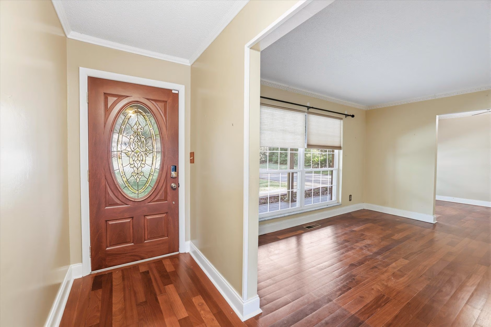Bright entryway with wooden door and hardwood floors.