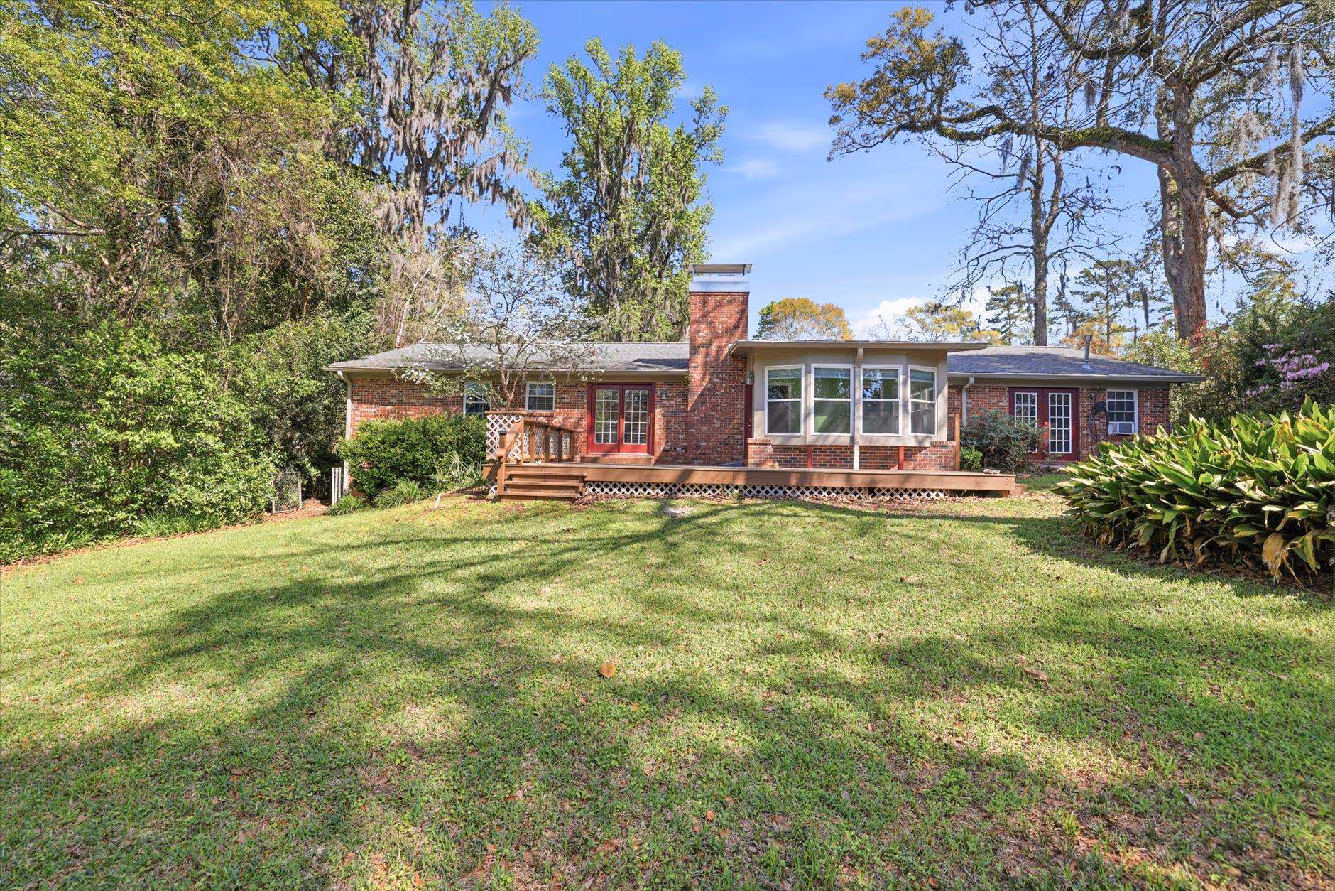 Single-story brick house with a large front yard and deck.