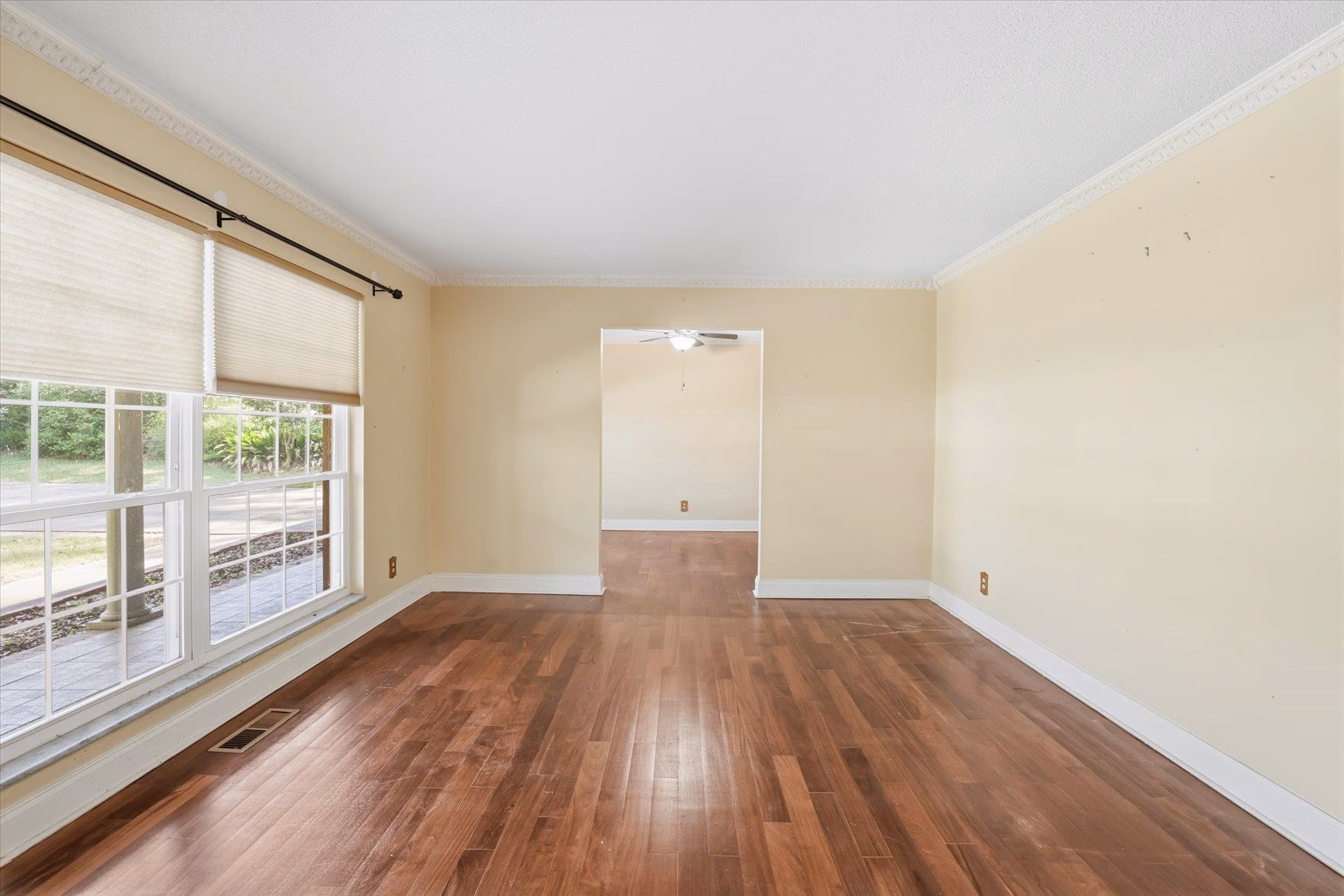 Empty living room with hardwood floors and beige walls.