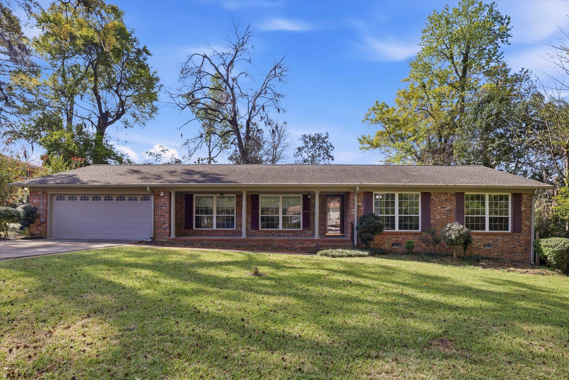Single-story brick house with a two-car garage and a spacious lawn.