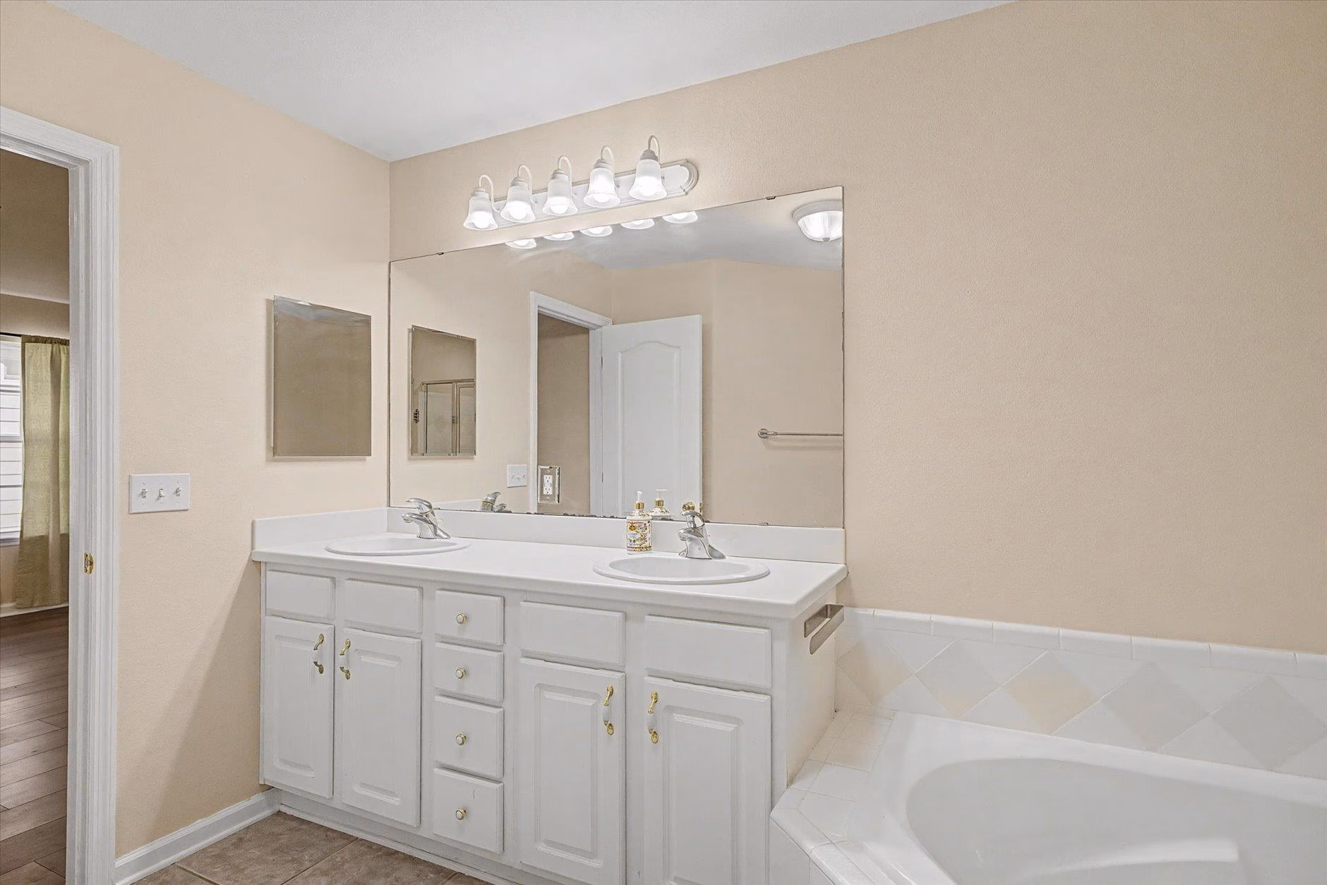 Bright bathroom with double sinks and white cabinetry.