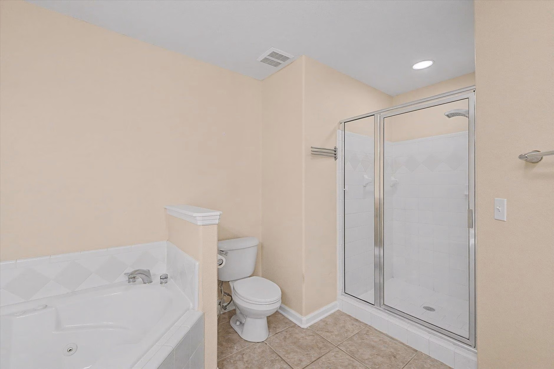 Clean bathroom with bathtub, toilet, and glass shower enclosure.