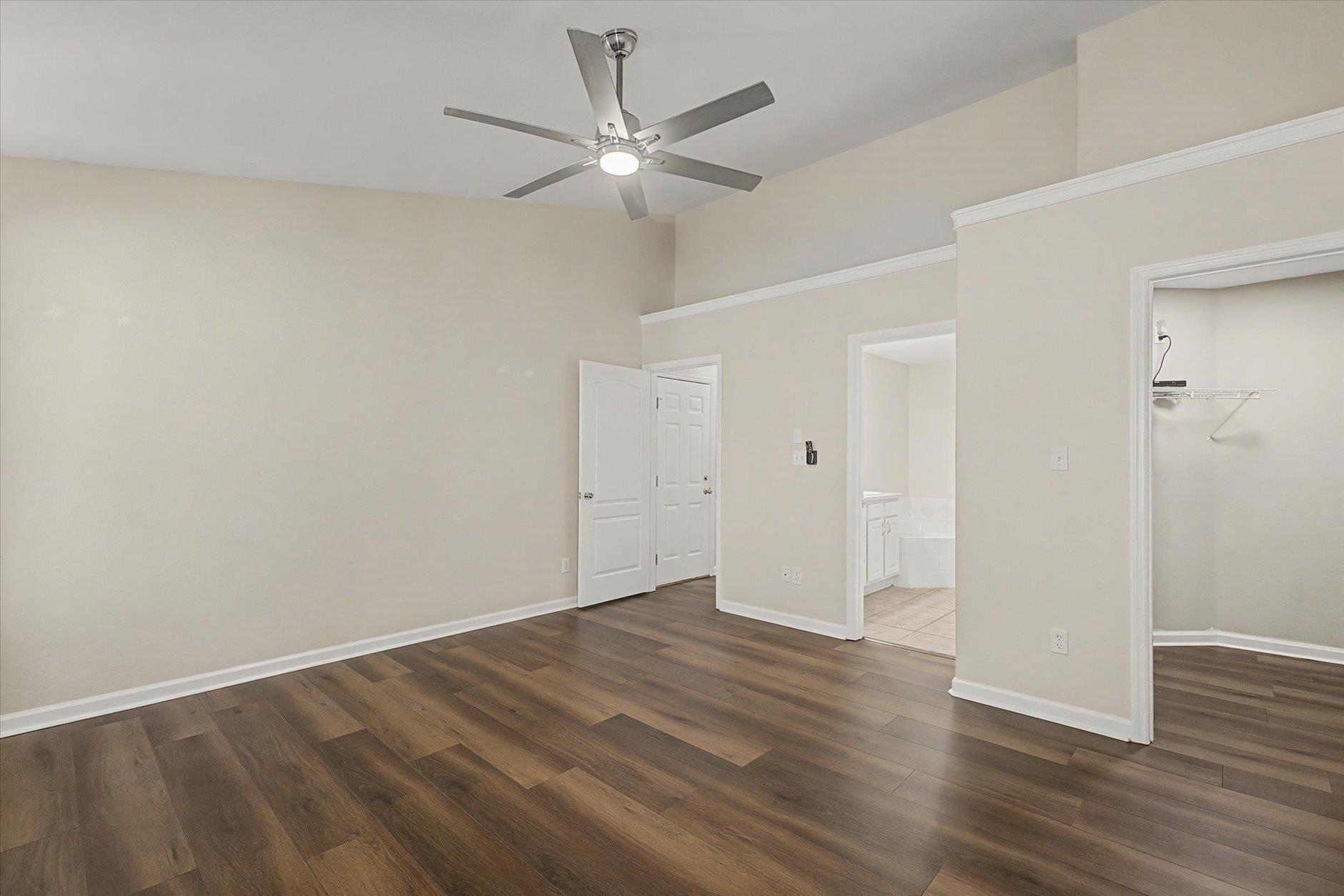 Empty room with wood flooring and ceiling fan.
