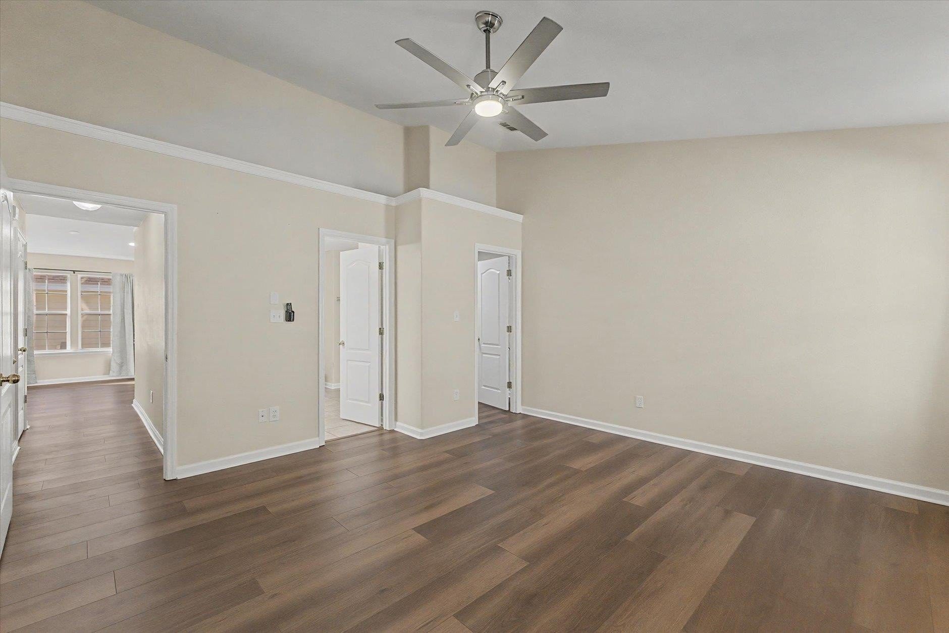 Empty room with hardwood floors and ceiling fan.