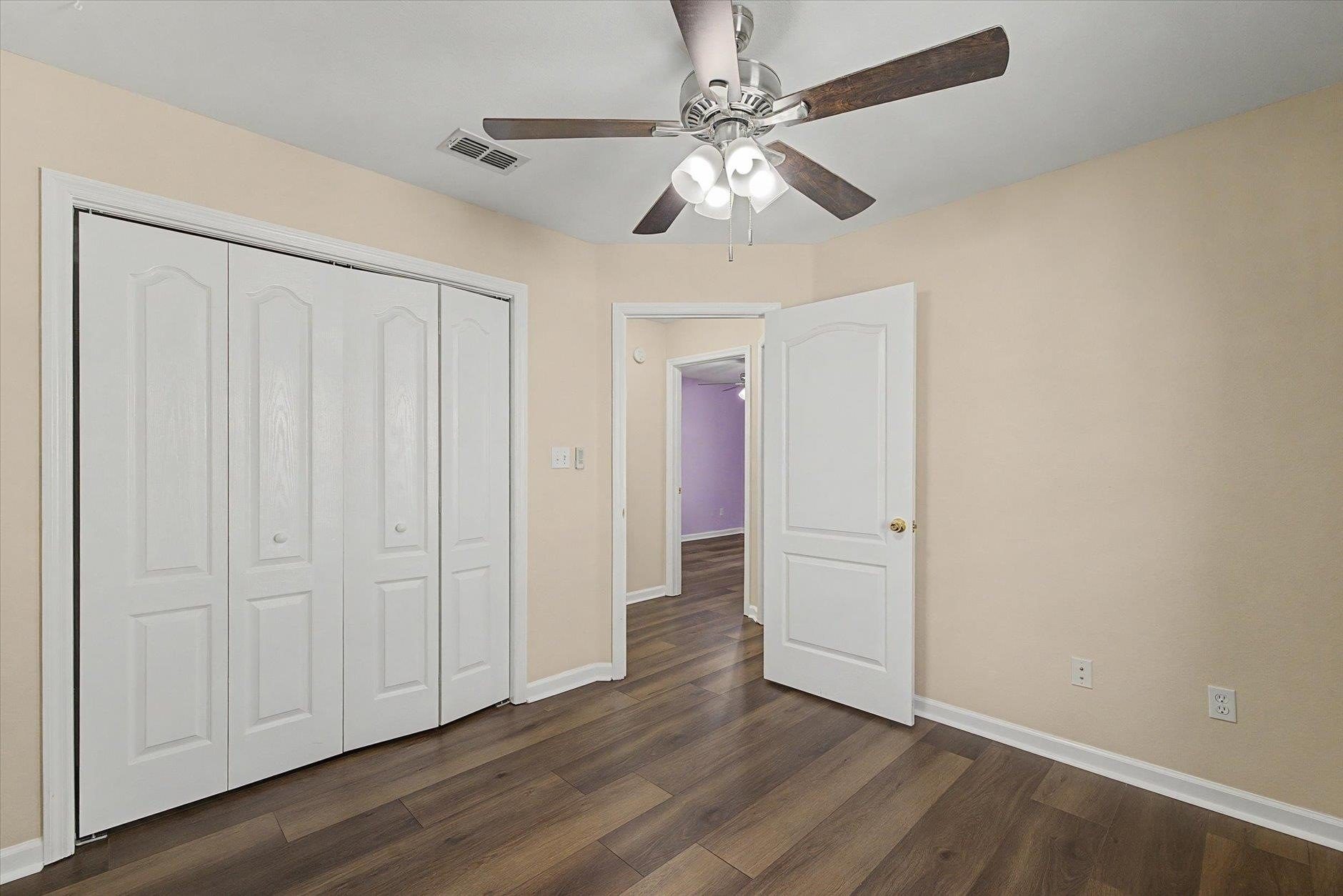 Empty room with ceiling fan and closet doors.