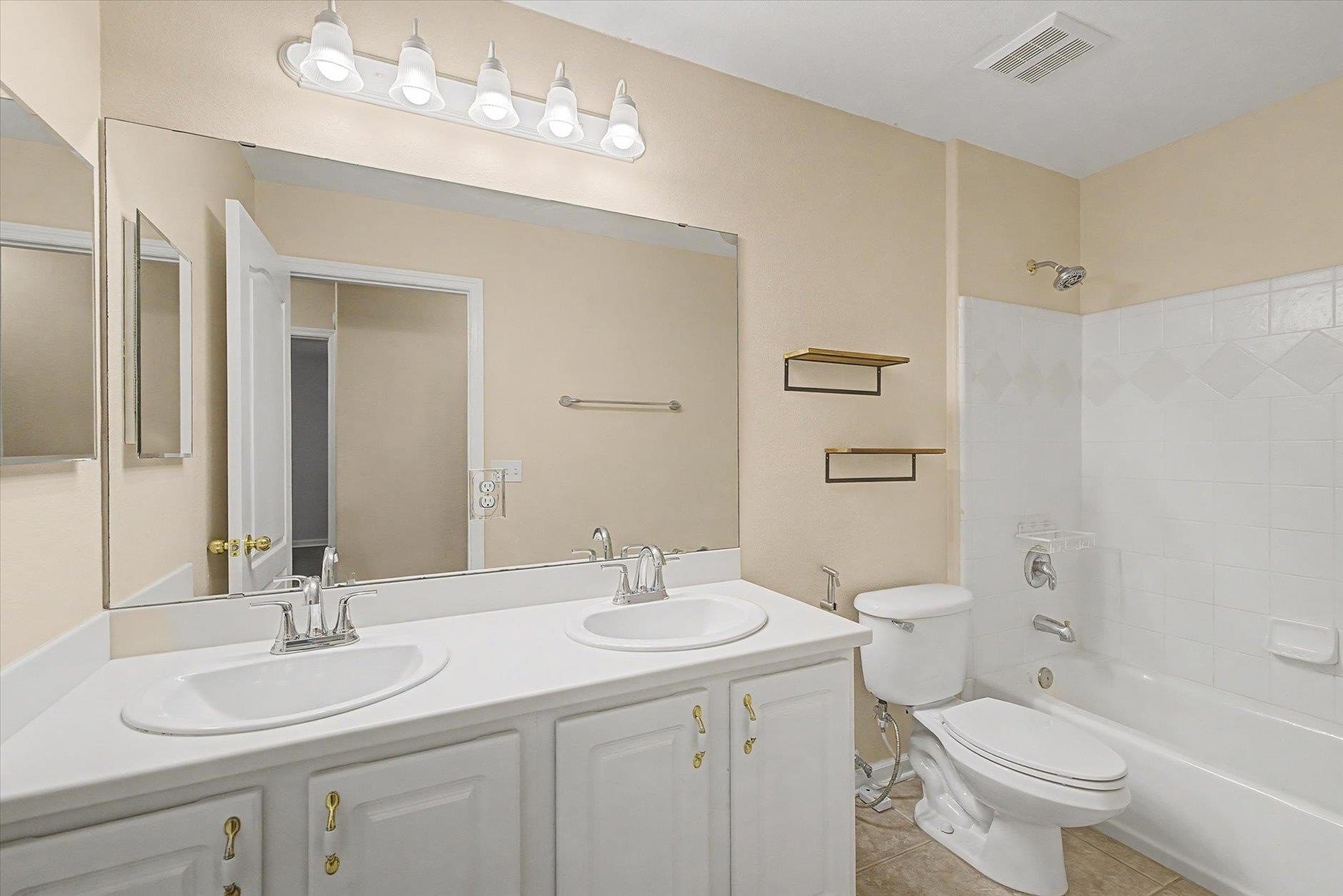 Clean bathroom with white vanity and bathtub.